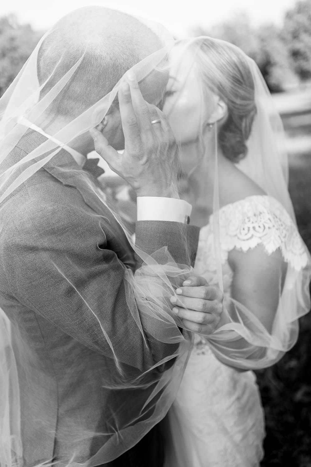 Hochzeitspaar unter Schleier küssend